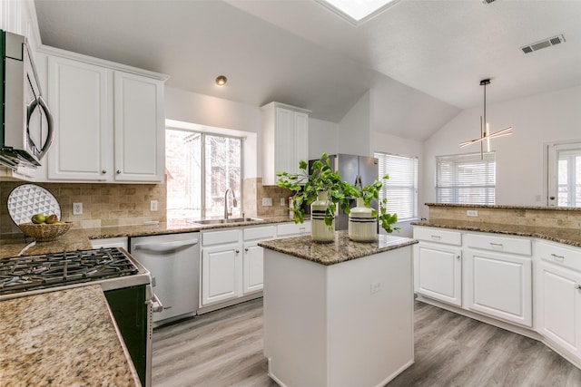 kitchen with stainless steel appliances, lofted ceiling, visible vents, light wood-style floors, and a sink