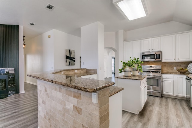 kitchen with stainless steel appliances, white cabinetry, light wood-style floors, visible vents, and a center island