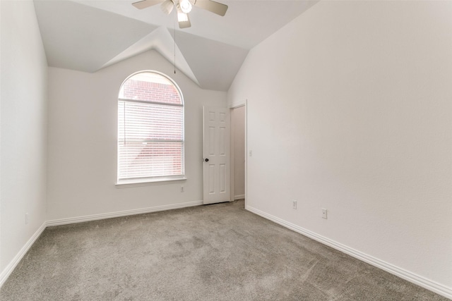 spare room with carpet, baseboards, vaulted ceiling, and a ceiling fan