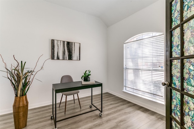 home office with light wood-style floors, lofted ceiling, and baseboards