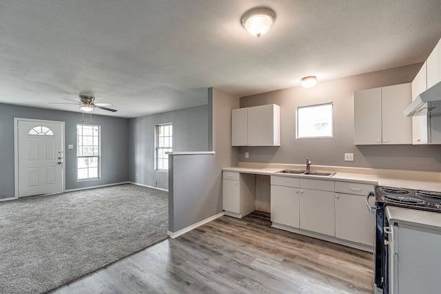 kitchen featuring light countertops, a sink, a textured ceiling, and black / electric stove