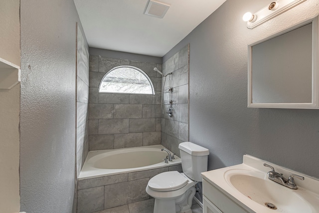 bathroom featuring a textured wall, toilet, vanity, visible vents, and tiled shower / bath