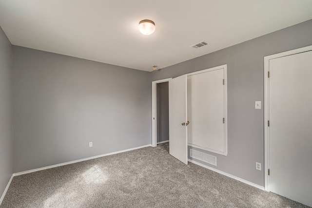 unfurnished bedroom with carpet flooring, visible vents, and baseboards