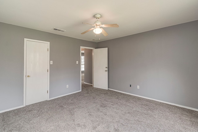 carpeted spare room with ceiling fan, visible vents, and baseboards