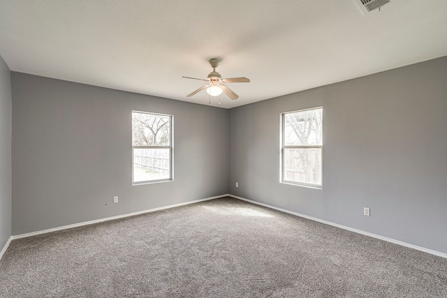 carpeted empty room featuring visible vents, baseboards, and a ceiling fan