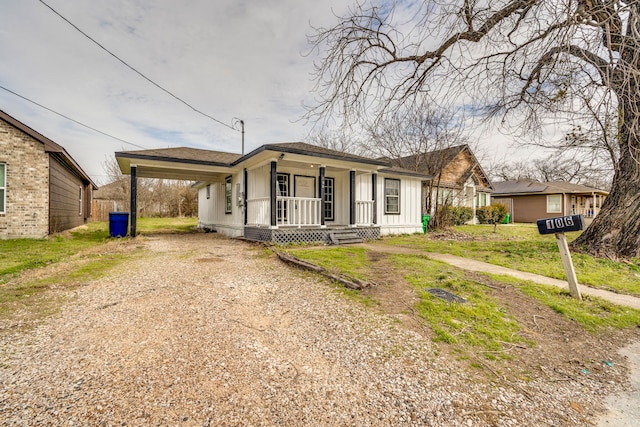 view of front facade featuring driveway, an attached carport, roof with shingles, covered porch, and board and batten siding