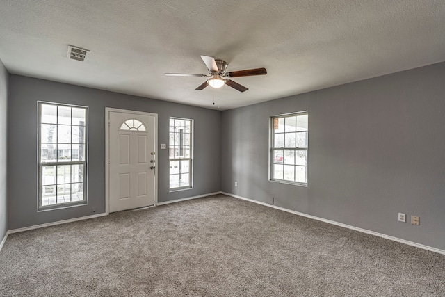 foyer with carpet, a textured ceiling, visible vents, and baseboards