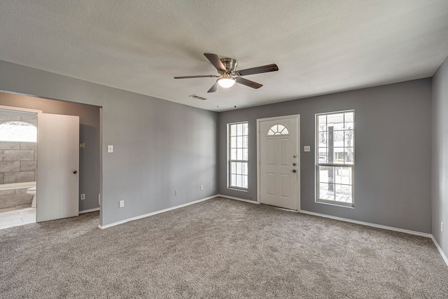 carpeted foyer featuring baseboards, ceiling fan, visible vents, and a textured ceiling