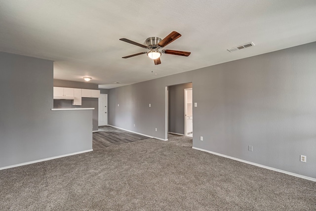 unfurnished living room featuring a ceiling fan, dark colored carpet, visible vents, and baseboards