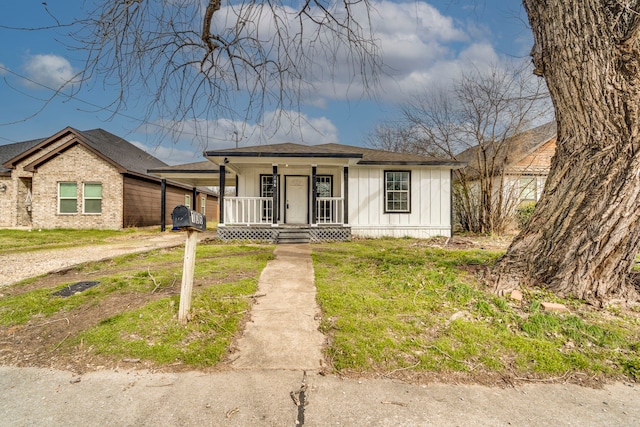 bungalow-style house with covered porch, driveway, an attached carport, and board and batten siding