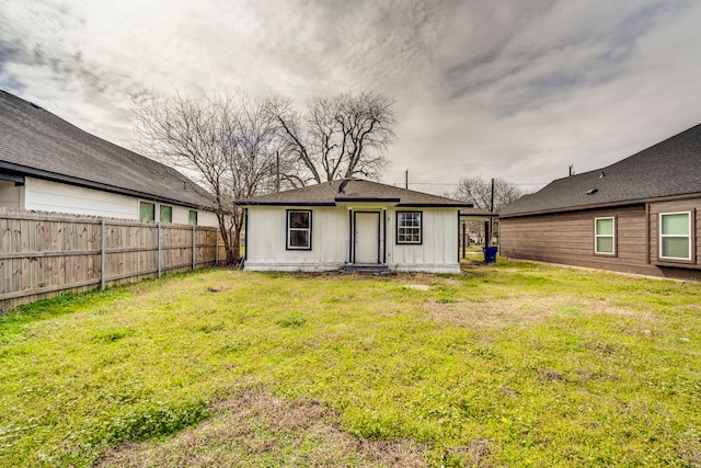 back of house with board and batten siding, a lawn, and fence