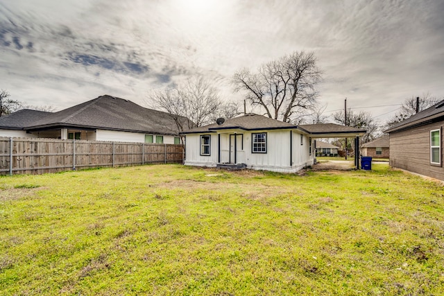 back of property featuring a yard, an attached carport, board and batten siding, and fence