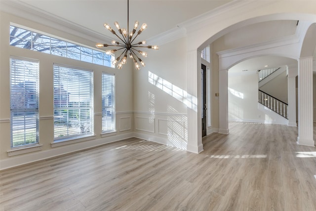 interior space with arched walkways, a notable chandelier, crown molding, and wood finished floors