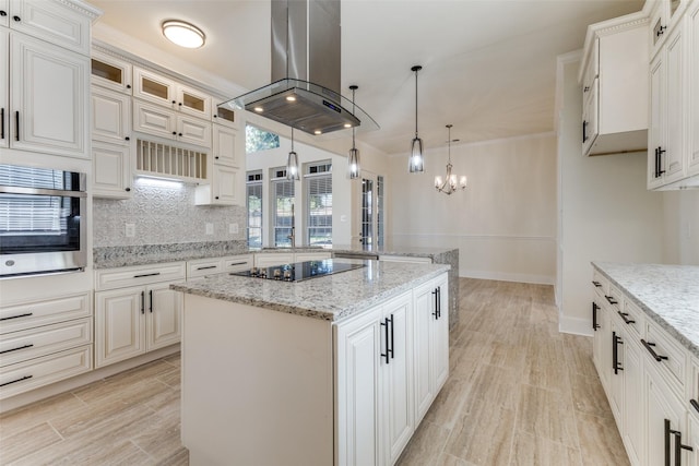 kitchen with black electric cooktop, island range hood, a peninsula, decorative backsplash, and a center island