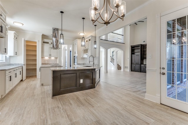 kitchen featuring arched walkways, crown molding, white cabinets, ventilation hood, and a chandelier