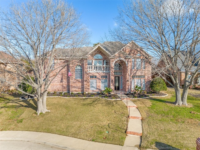 view of front of property featuring brick siding, a balcony, and a front lawn