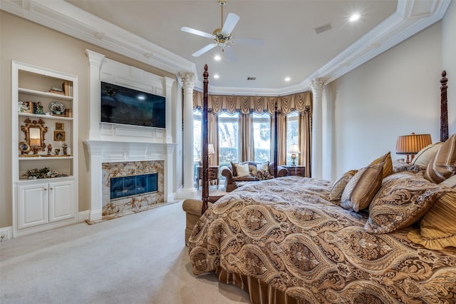 carpeted bedroom with a premium fireplace, visible vents, ornamental molding, and ornate columns