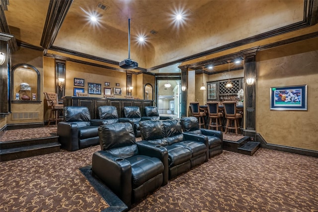 carpeted cinema with visible vents, vaulted ceiling, ornamental molding, wet bar, and a textured wall