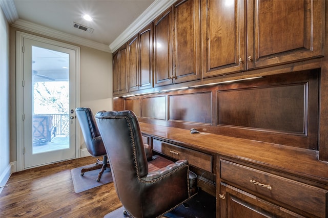 office area featuring crown molding, wood finished floors, visible vents, and built in desk