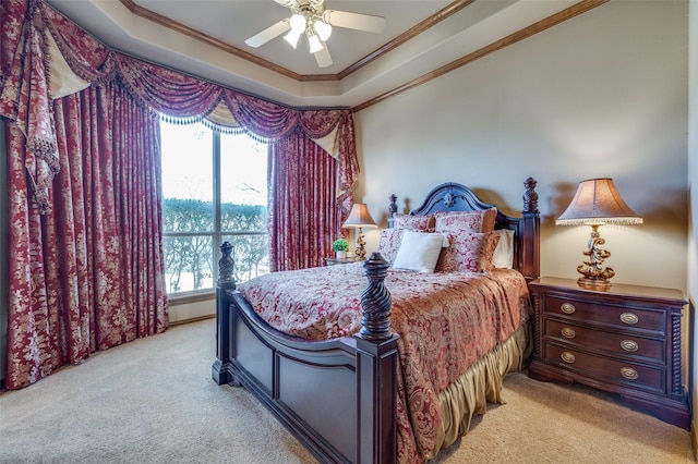 bedroom with a raised ceiling, light colored carpet, ornamental molding, and a ceiling fan