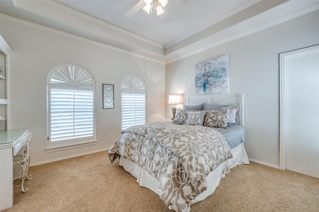 carpeted bedroom featuring ceiling fan, baseboards, crown molding, and a tray ceiling