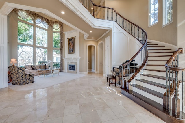 foyer entrance featuring a high ceiling, arched walkways, and ornamental molding