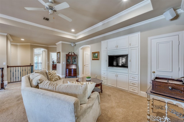 living room with arched walkways, light colored carpet, and a raised ceiling