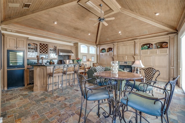 dining room with stone tile floors, lofted ceiling with beams, bar, wood ceiling, and crown molding