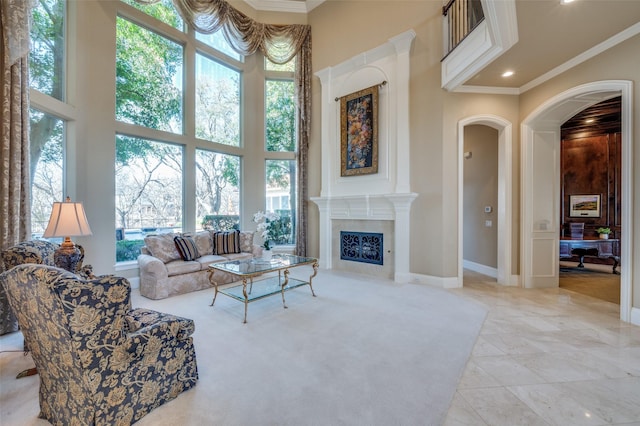 living room with a high end fireplace, arched walkways, a high ceiling, and crown molding