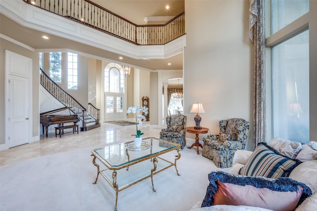 living area with baseboards, stairway, ornamental molding, a towering ceiling, and a notable chandelier