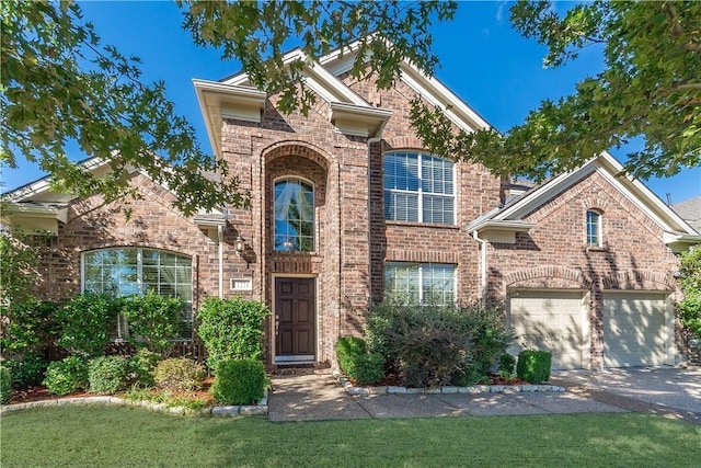 traditional-style home with a garage, driveway, brick siding, and a front yard