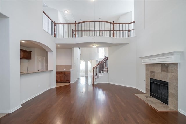 unfurnished living room with dark wood-type flooring, stairway, and baseboards