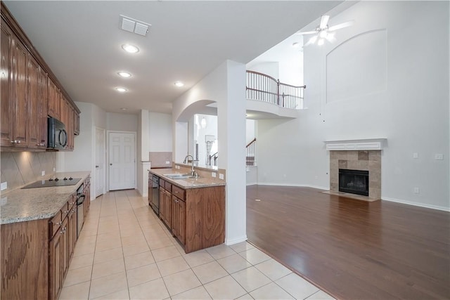 kitchen featuring visible vents, backsplash, open floor plan, a sink, and black appliances