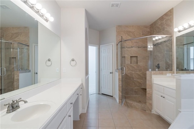 full bathroom featuring a stall shower, two vanities, a sink, and visible vents