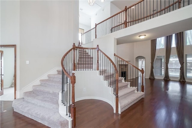 stairway featuring wood finished floors and a towering ceiling