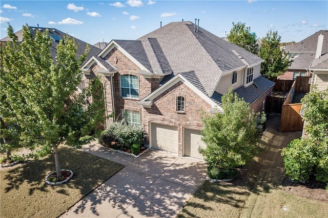 view of front of property featuring brick siding, a shingled roof, fence, a garage, and driveway