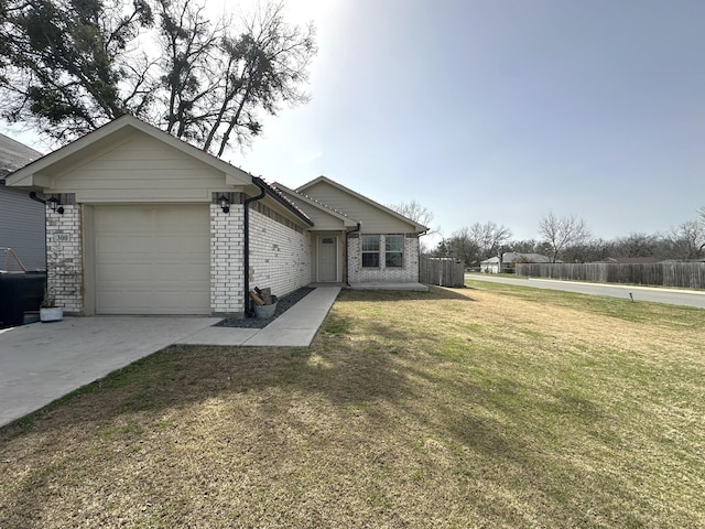 view of front of home with brick siding, concrete driveway, a front yard, fence, and a garage