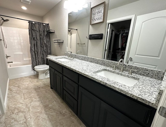 bathroom with visible vents, double vanity, a sink, and toilet