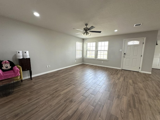 foyer entrance featuring dark wood-style flooring, visible vents, ceiling fan, a textured ceiling, and baseboards