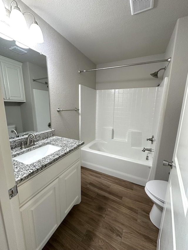 full bath with toilet, a textured ceiling, visible vents, and wood finished floors