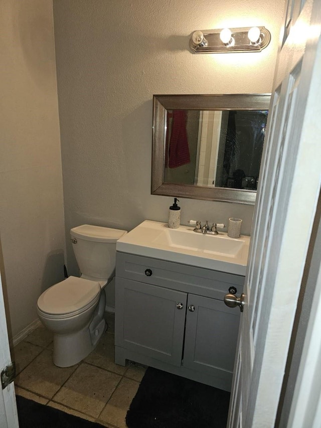 bathroom with a textured wall, vanity, tile patterned flooring, and toilet