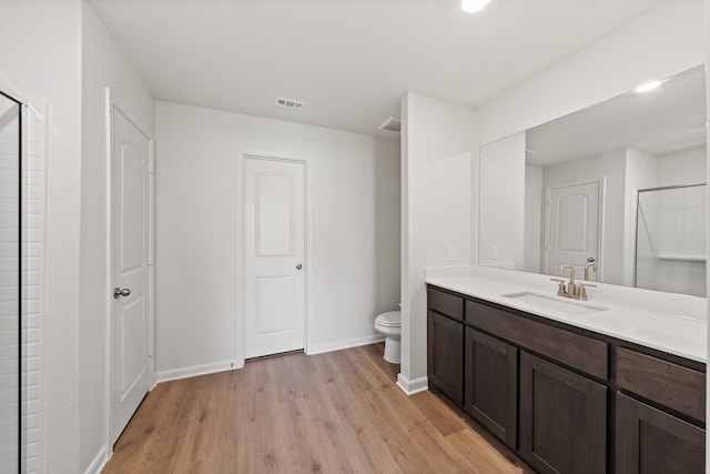 full bathroom featuring visible vents, toilet, wood finished floors, an enclosed shower, and vanity