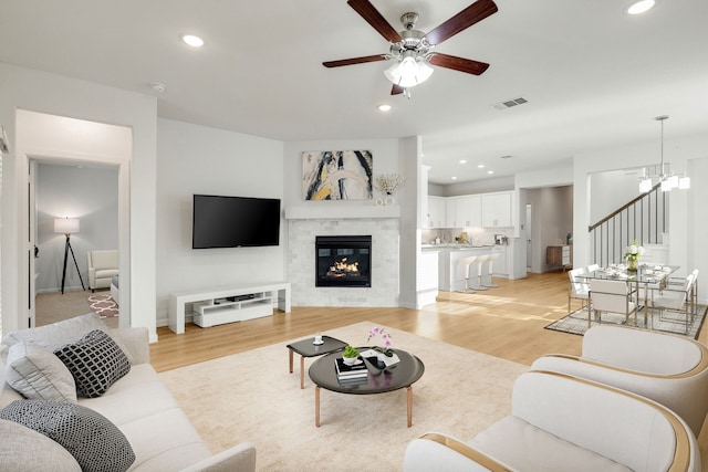 1536 Wolfberry Ln, Northlake, TX 76226 - living room featuring light wood-style flooring, ceiling fan, recessed lighting, stairs, and a glass covered fireplace