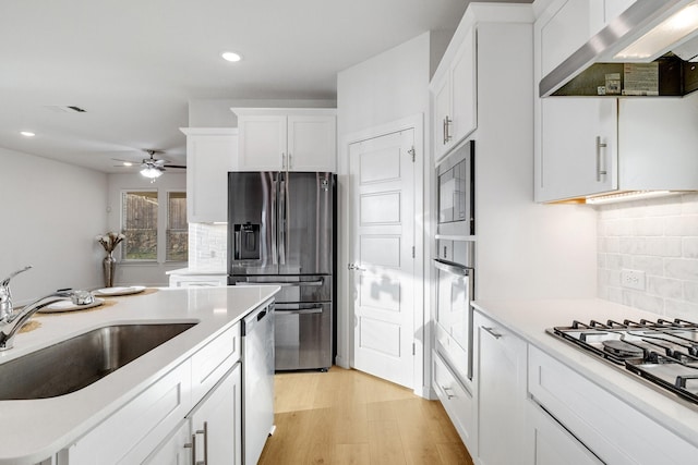 1536 Wolfberry Ln, Northlake, TX 76226 - kitchen featuring wall chimney exhaust hood, stainless steel appliances, a sink, a ceiling fan, and white cabinetry