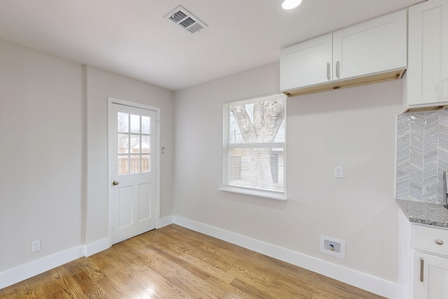 unfurnished dining area featuring light wood-type flooring, baseboards, and visible vents