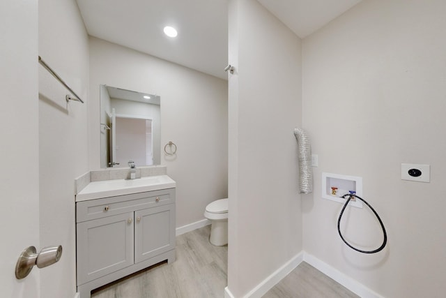 bathroom with baseboards, toilet, wood finished floors, vanity, and recessed lighting