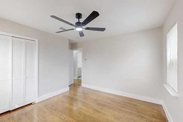 unfurnished bedroom featuring baseboards, multiple windows, and light wood finished floors