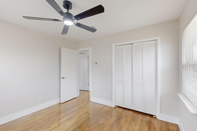 unfurnished bedroom featuring a ceiling fan, light wood-style flooring, baseboards, and a closet