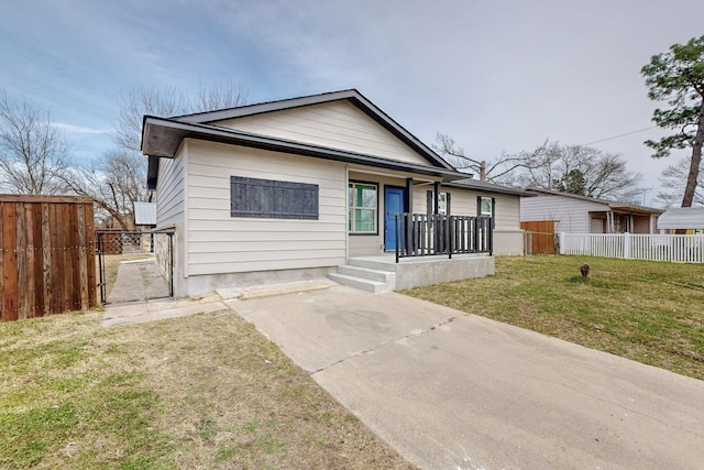 view of front of home featuring covered porch, fence, and a front lawn