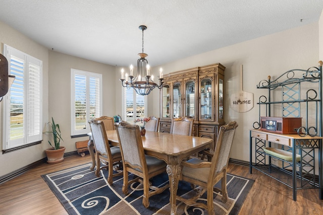 dining space with a notable chandelier, a textured ceiling, baseboards, and wood finished floors